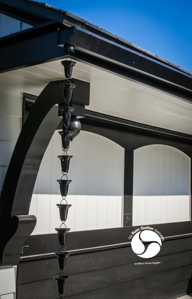 Black rain chain installation on white and black custom home by The Rain Gutter Specialists in Los Angeles