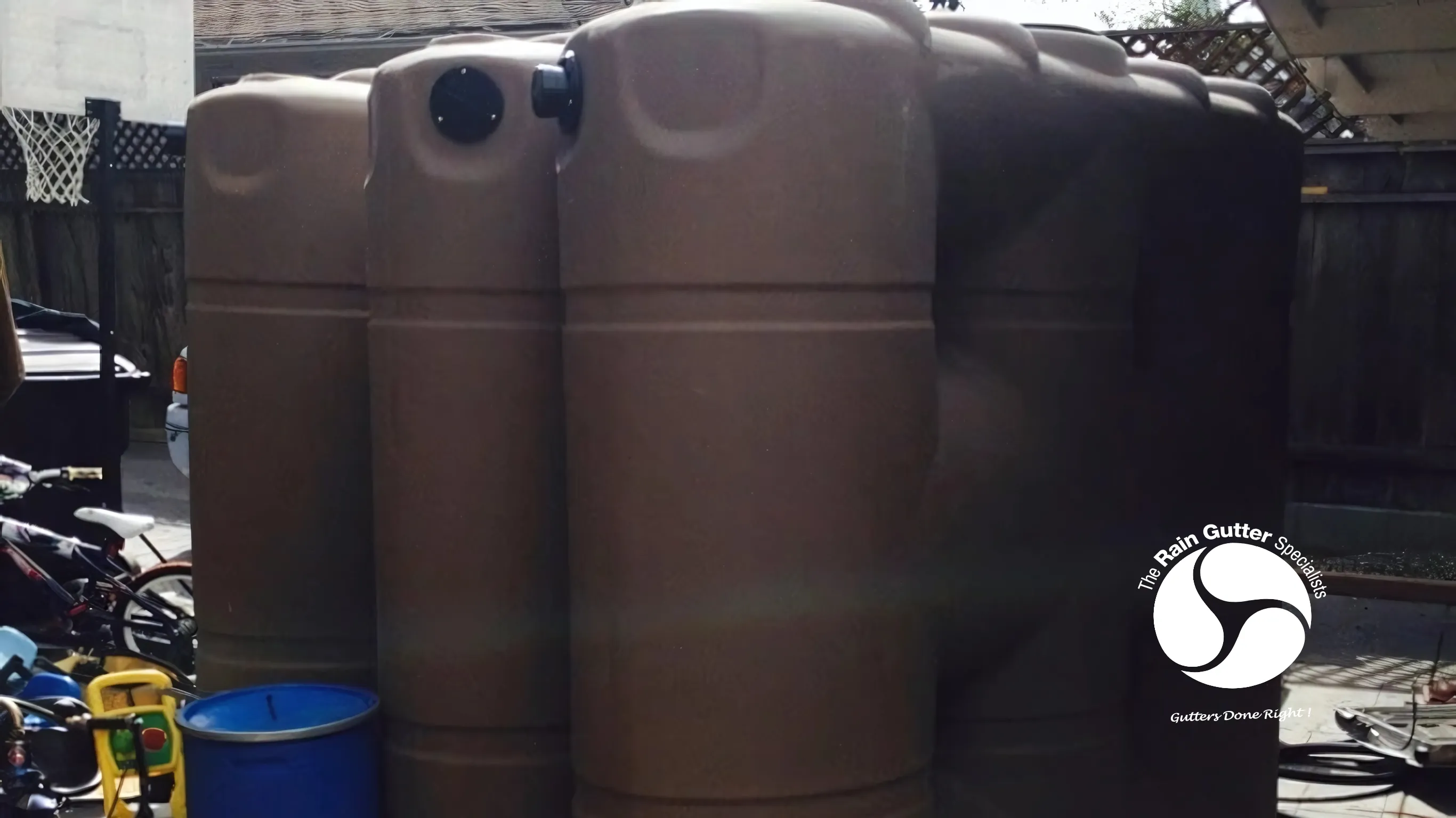Rain barrels connected to downspouts for garden water reuse