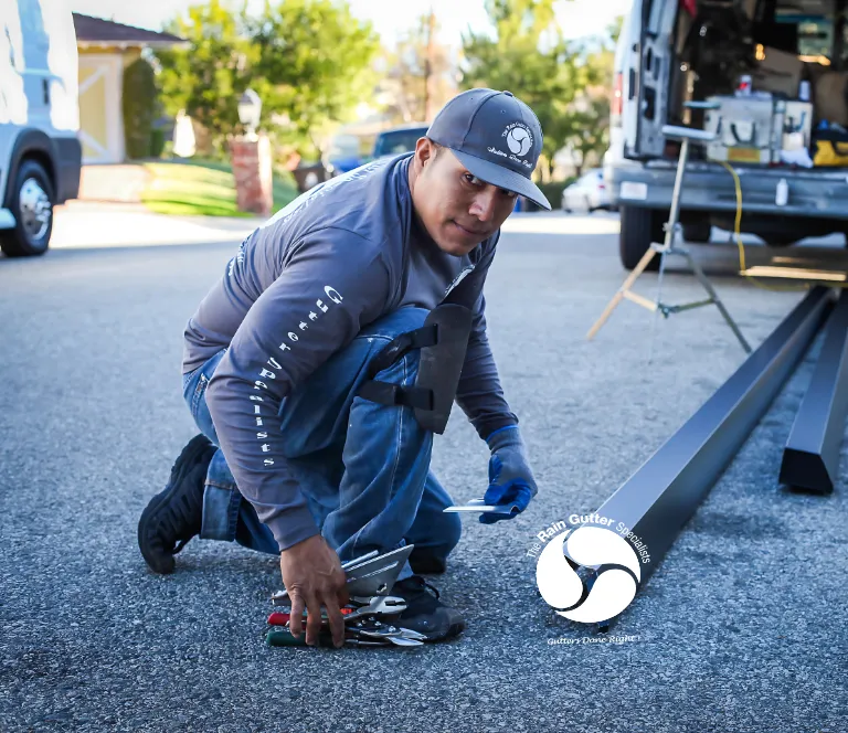 Rain Gutter Specialists team member preparing aluminum gutter materials on-site during Los Angeles installation